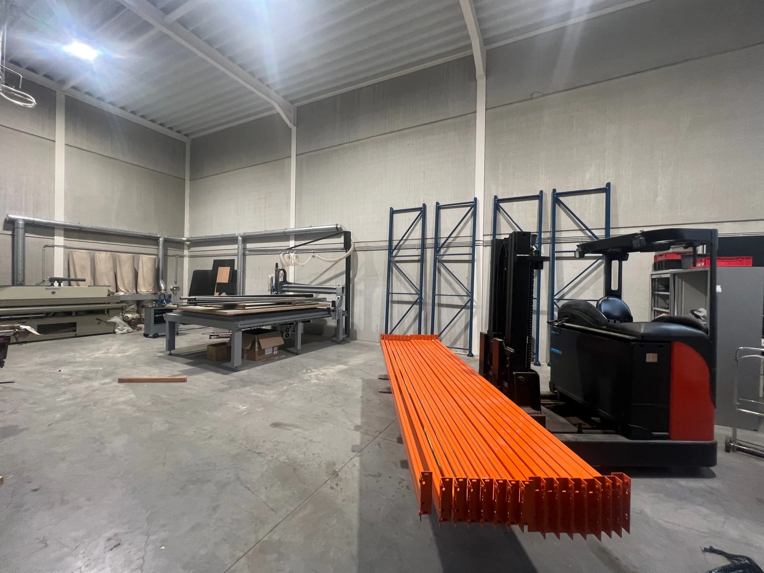 Zicht op de werkvloer met de freesmachine en, links achteraan, de kantenaanlijmmachine