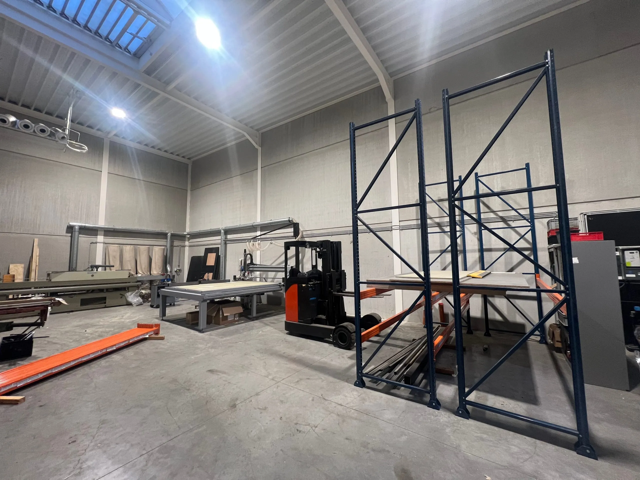 De werkvloer van het atelier van Gila Interieur met de freesmachine en de magazijnrekken
