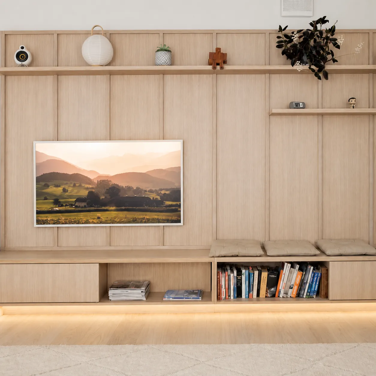 Gepaneelde tv-wand op maat in eiken met open vakken en een verlichte plint
